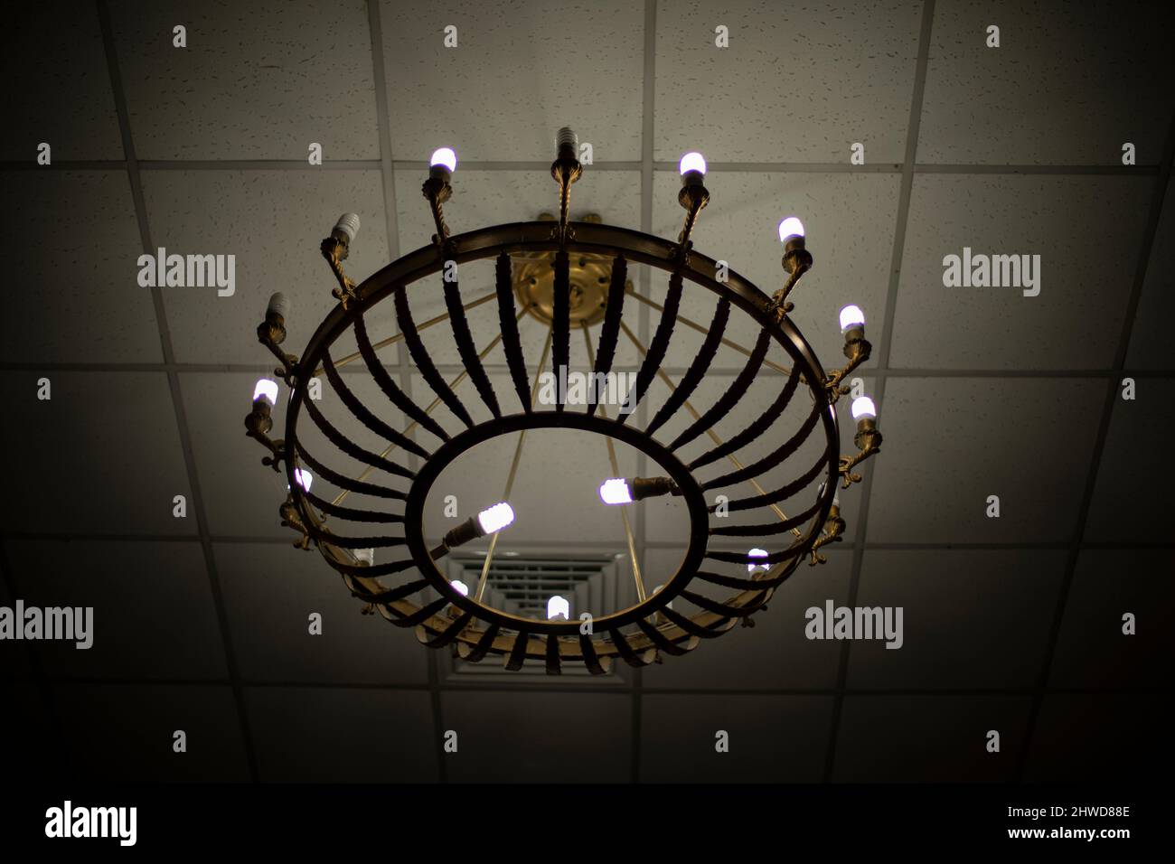 Antico lampadario sul soffitto. Dettagli interni. Lampadario per candele. Sorgente luminosa nella sala. Foto Stock