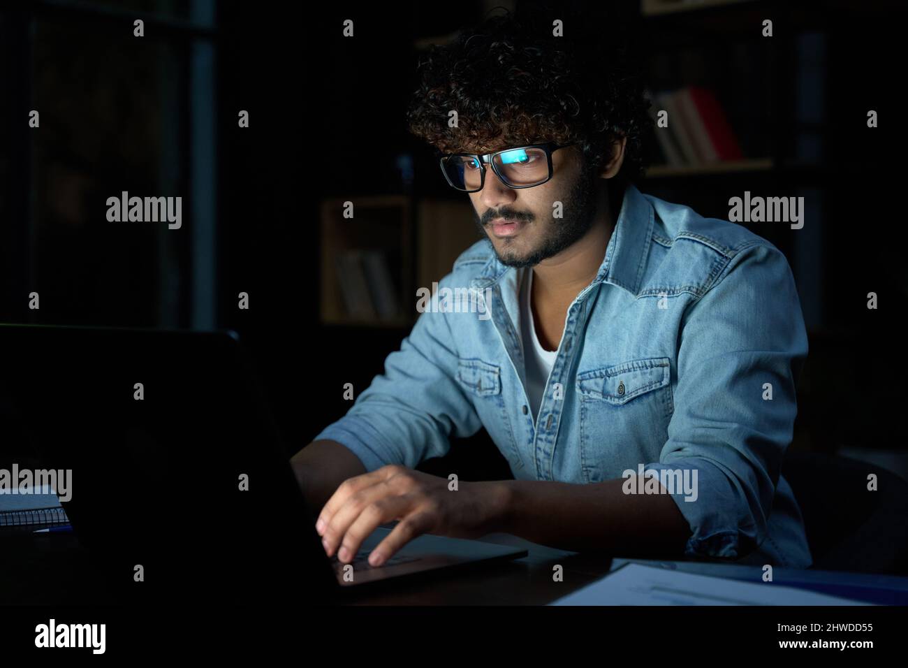 Un uomo d'affari indiano concentrato che lavora online di notte con un notebook. Foto Stock