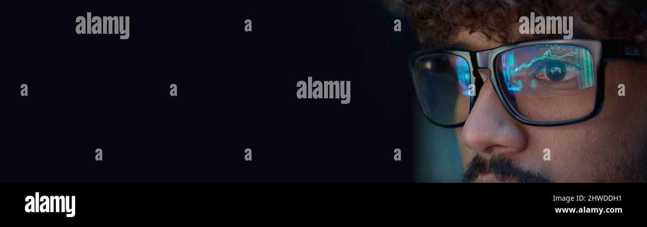 Giovane uomo che indossa occhiali guardando le carte commerciali che riflettono negli occhiali. Foto Stock