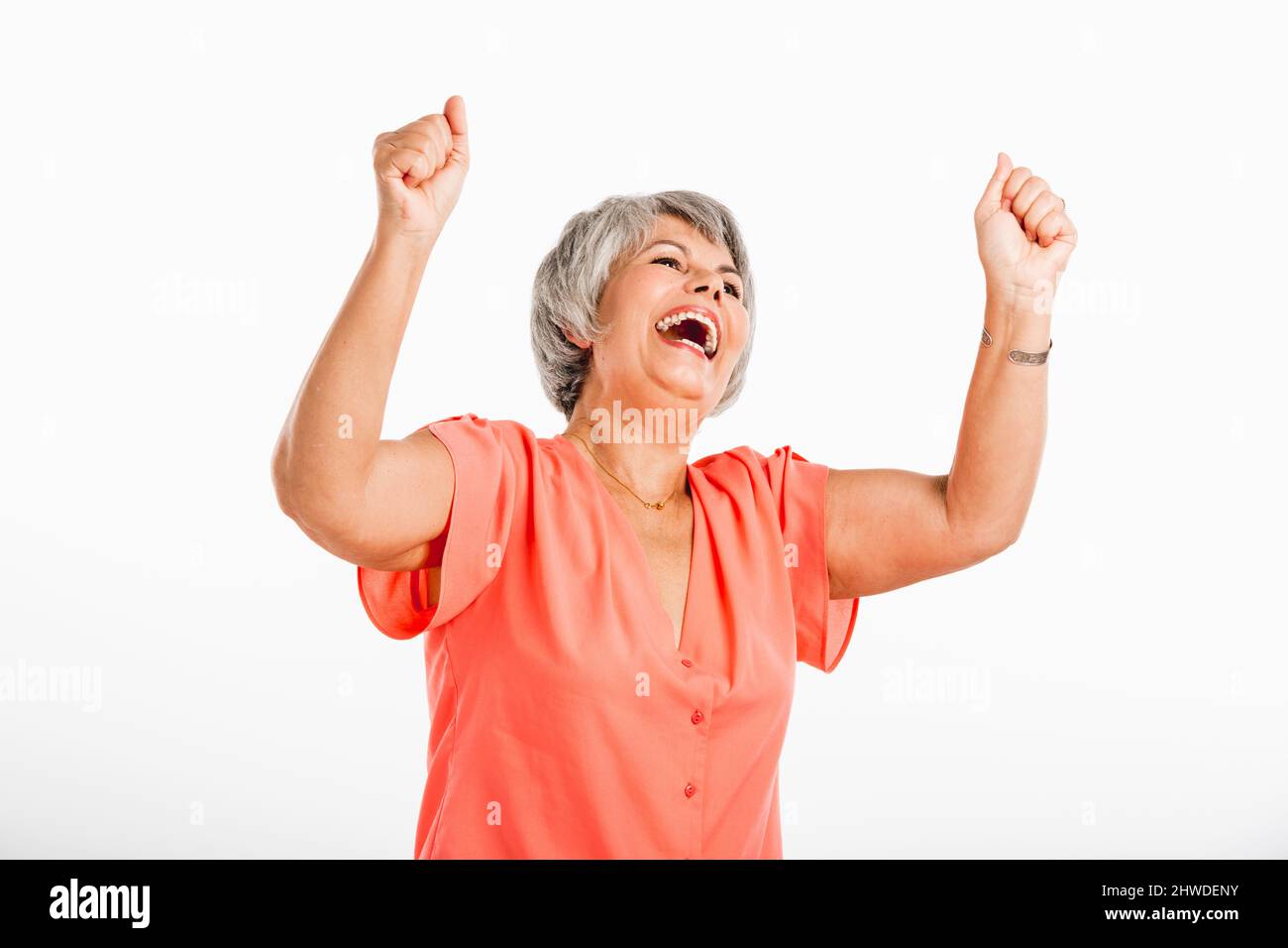 Felice vecchia donna con entrambe le braccia in aria, isolato su sfondo bianco Foto Stock
