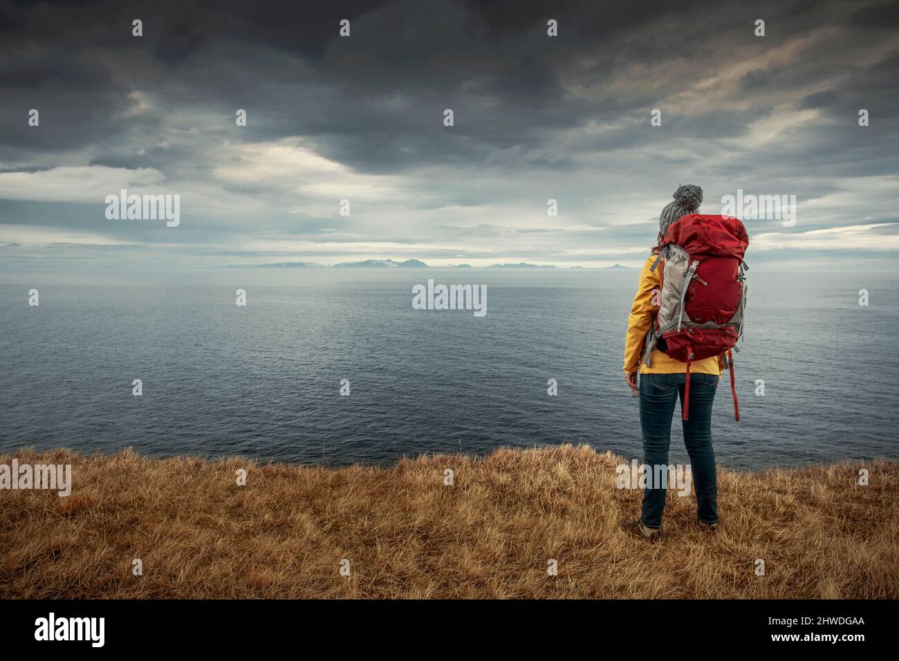 Viaggiatore saccopelatore femminile in Islanda guardando l'Oceano Foto Stock