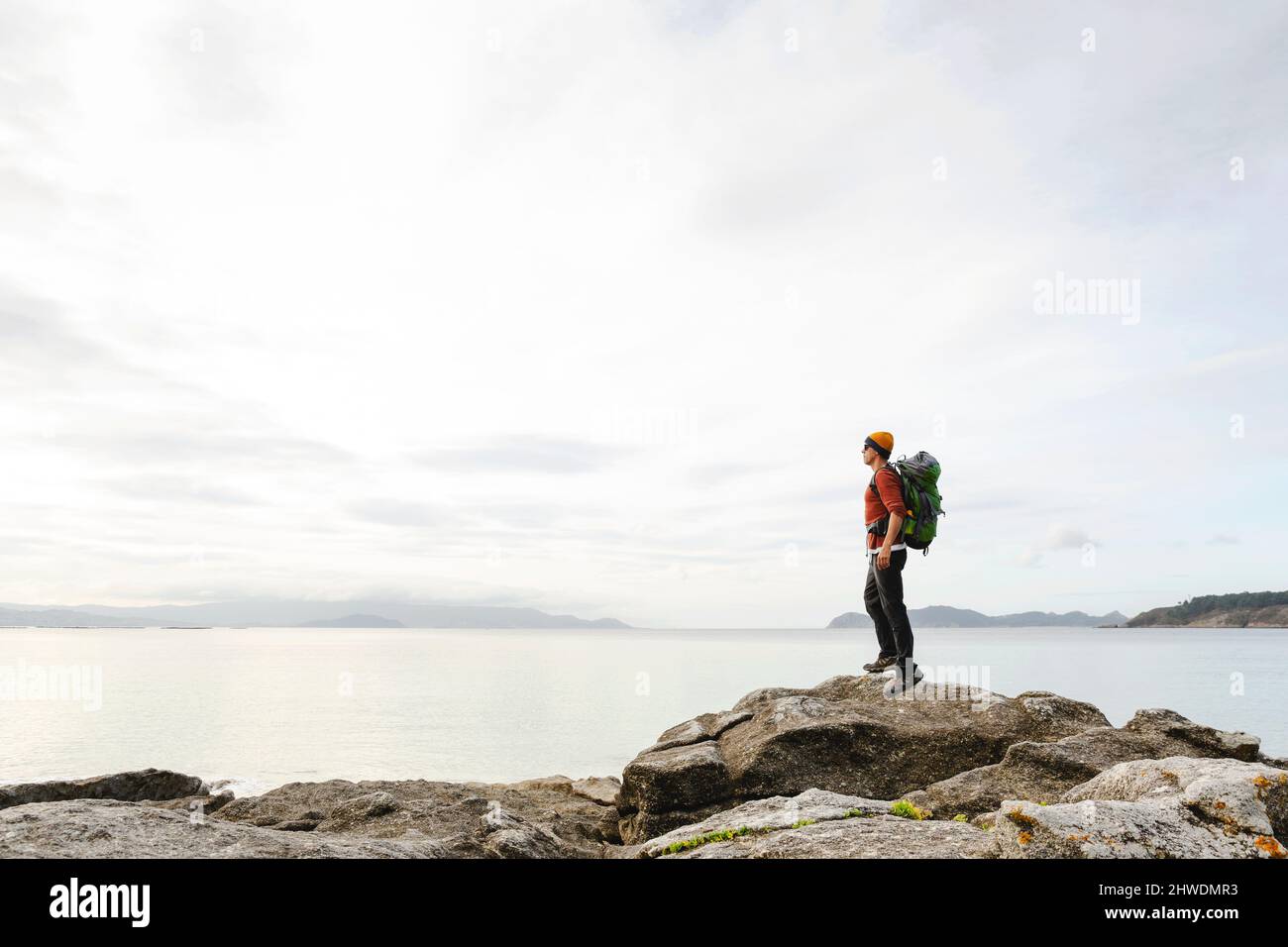 Uomo con backoack godendo della vista mattutina della costa Foto Stock