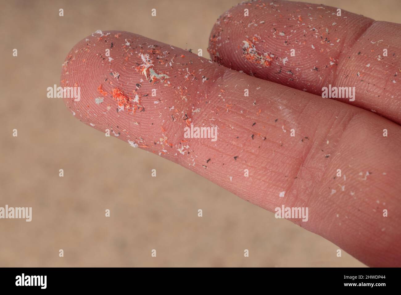Il primo piano delle microplastica si trova sul dito dell'essere umano. Piccoli pellet di plastica a dito. Micro plastica, problema. Foto Stock