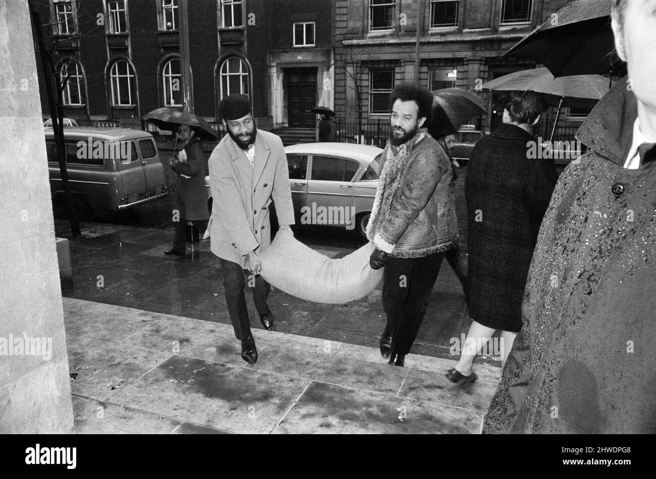 Gli studenti che occupano la sede centrale dell'Unione della London University a Malet Street, tengono un incontro per formulare i futuri piani d'azione. I manifestanti hanno detto che volevano costituire una base rivoluzionaria e istituire una London School of Economics in esilio, la LSE è stata chiusa a seguito di proteste da parte di studenti arrabbiati per l'installazione di cancelli di sicurezza in acciaio. Nella foto, Michael De Freitas (Michael X) sulla destra, e collega che consegna un sacco di riso alla sede centrale dell'ULU. 28th gennaio 1969. Foto Stock