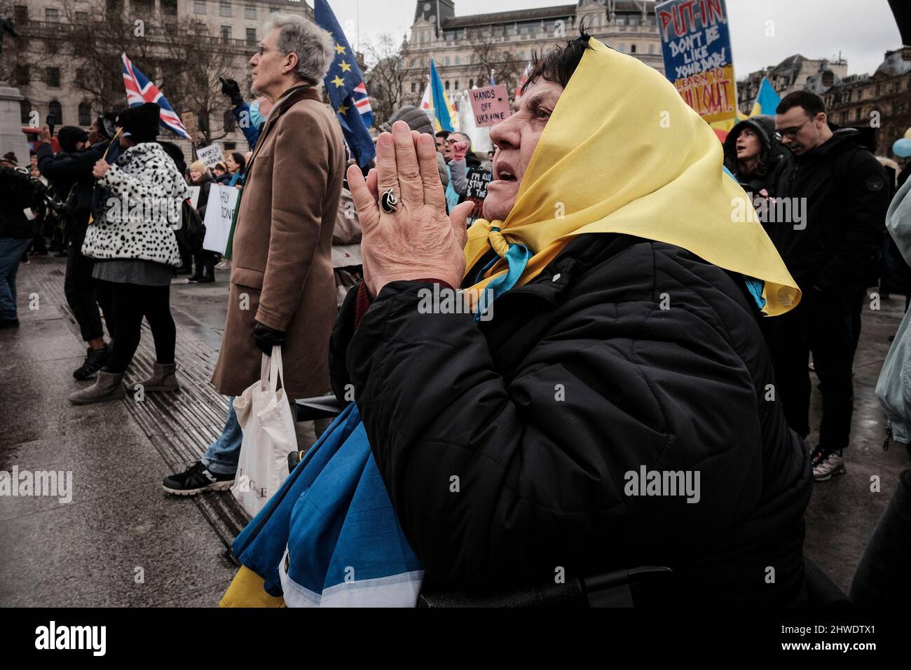 5th marzo 2022, Londra, Regno Unito. Cittadini ucraini e sostenitori pro-Ucraina si radunano a Trafalgar Square per protestare contro l'invasione russa e la guerra in Ucraina. Donna anziana drappeggiato in bandiera Ucraina tenere le mani insieme in preghiera. Foto Stock