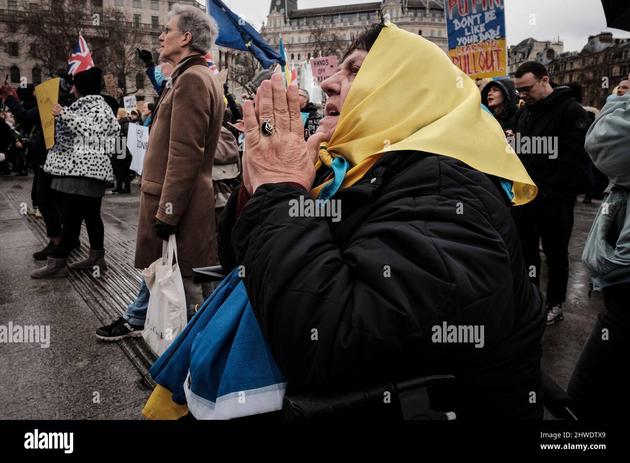 5th marzo 2022, Londra, Regno Unito. Cittadini ucraini e sostenitori pro-Ucraina si radunano a Trafalgar Square per protestare contro l'invasione russa e la guerra in Ucraina. Donna anziana drappeggiato in bandiera Ucraina tenere le mani insieme in preghiera. Foto Stock