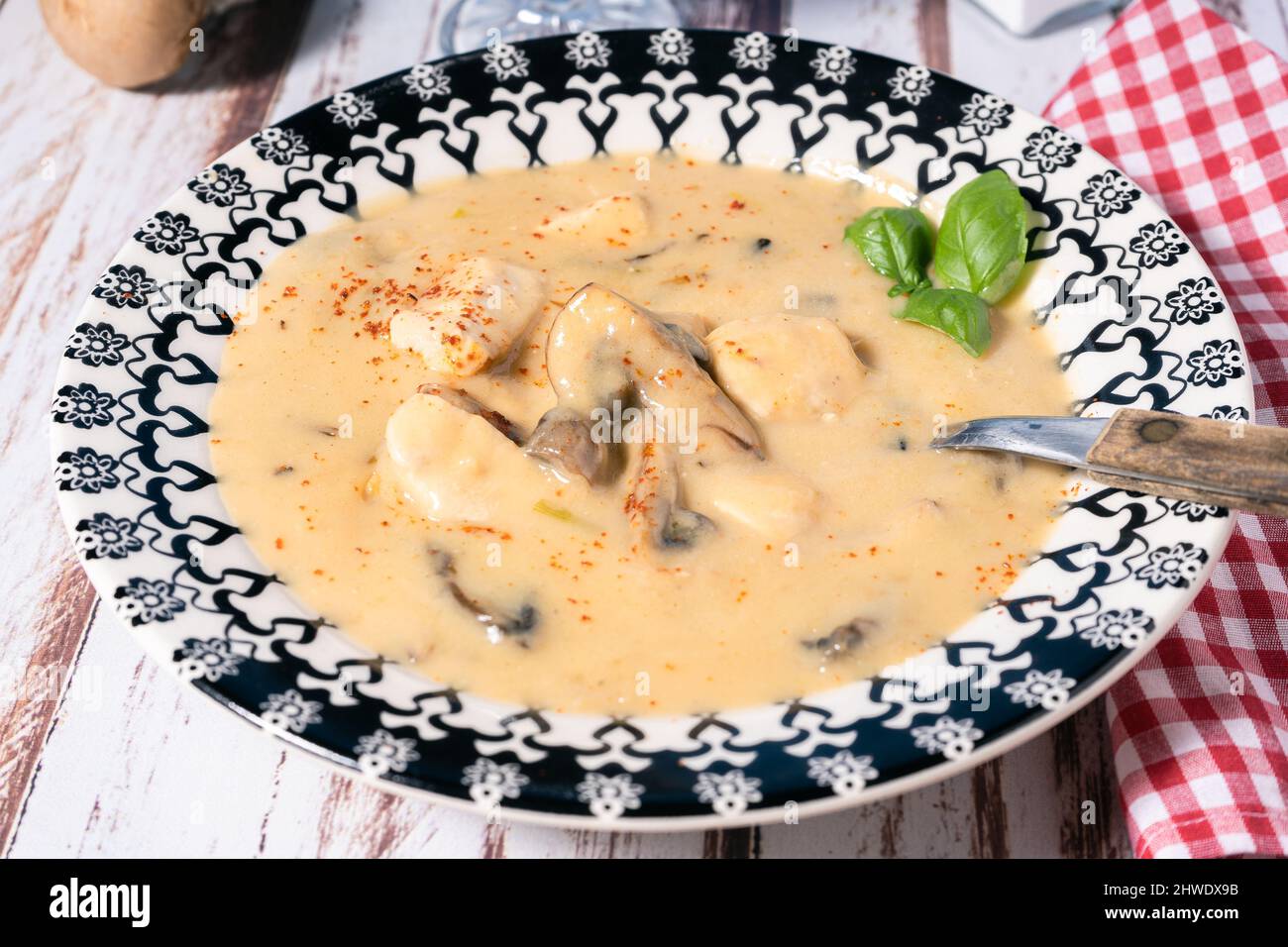 Una crema fatta in casa di zuppa di pollo e funghi o fricassea di pollo alla francese, in un recipiente per zuppa su un tavolo di legno. Vista alta. Foto Stock