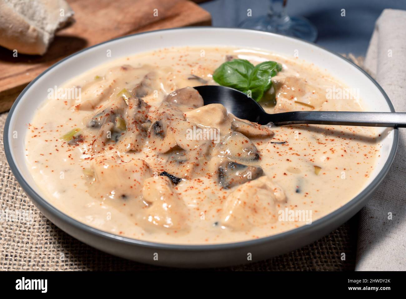 Una crema fatta in casa di zuppa di pollo e funghi o fricassea di pollo alla francese, in un recipiente per zuppa su un tavolo di legno. Vista alta. Foto Stock