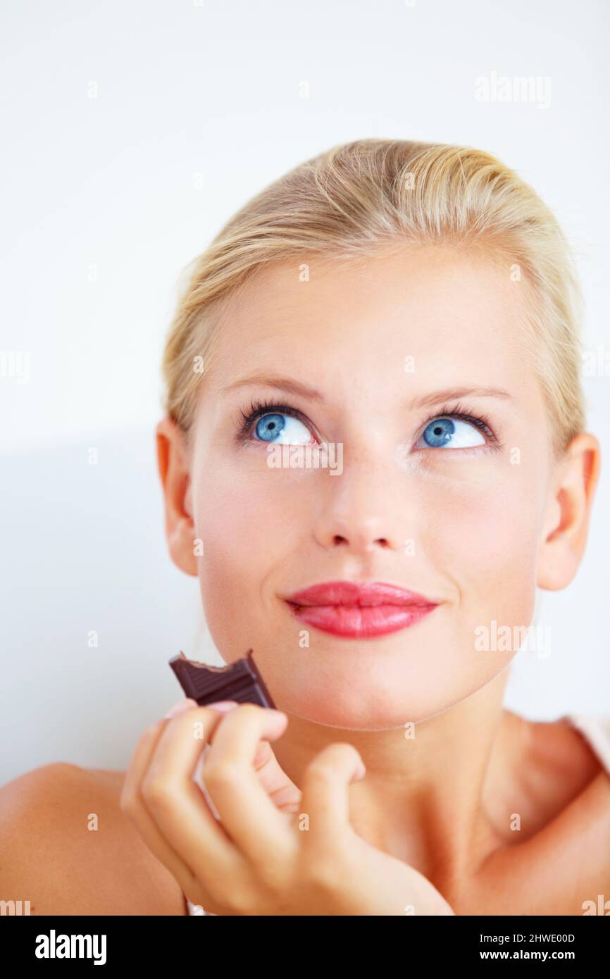 MMM, questo è celeste. Giovane donna sorridente che gode di un delizioso pezzo di cioccolato. Foto Stock