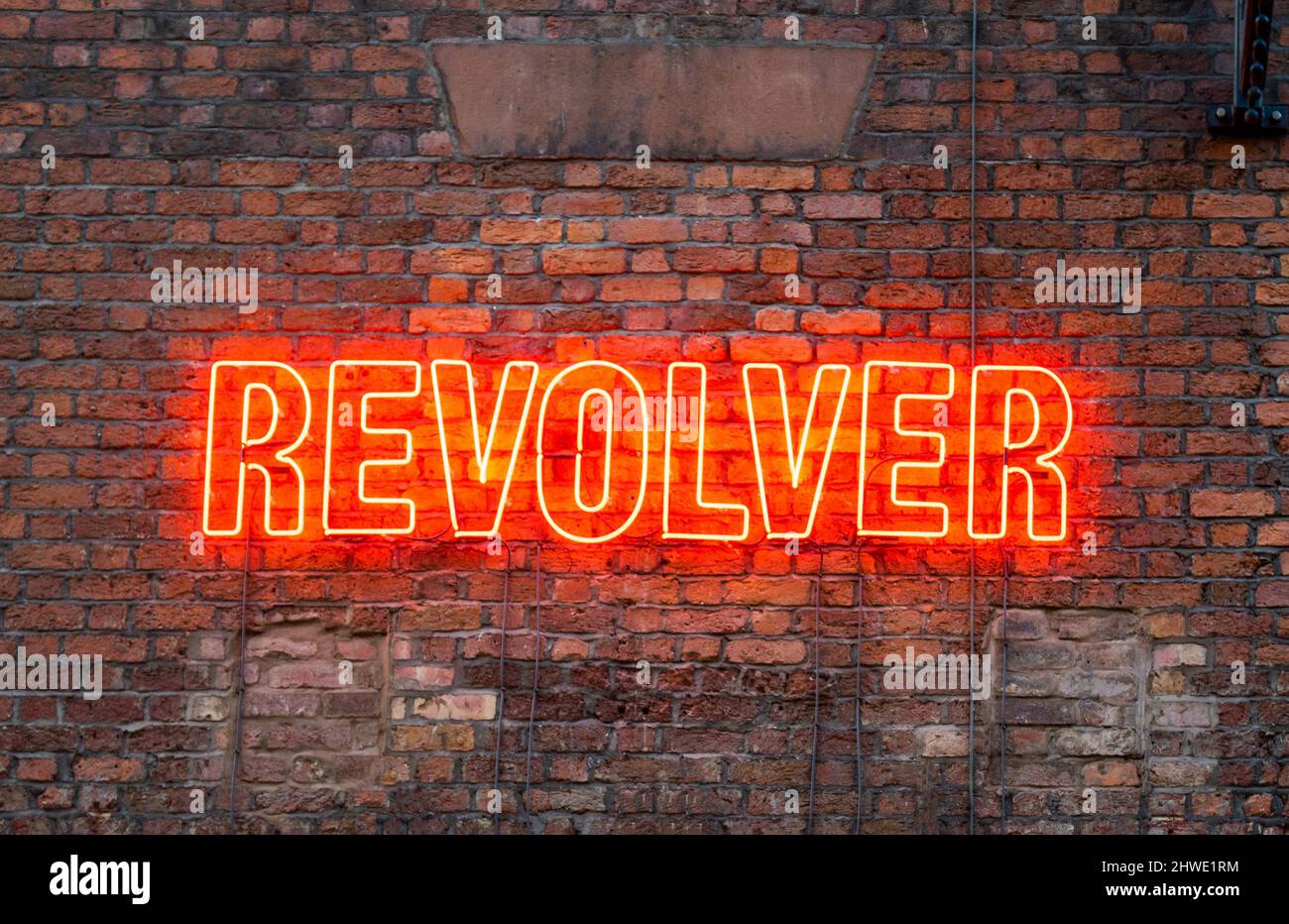 Cartello illuminato su una parete di mattoni fuori da Revolver, un music bar nell'area dei Liverpool Beatles Foto Stock