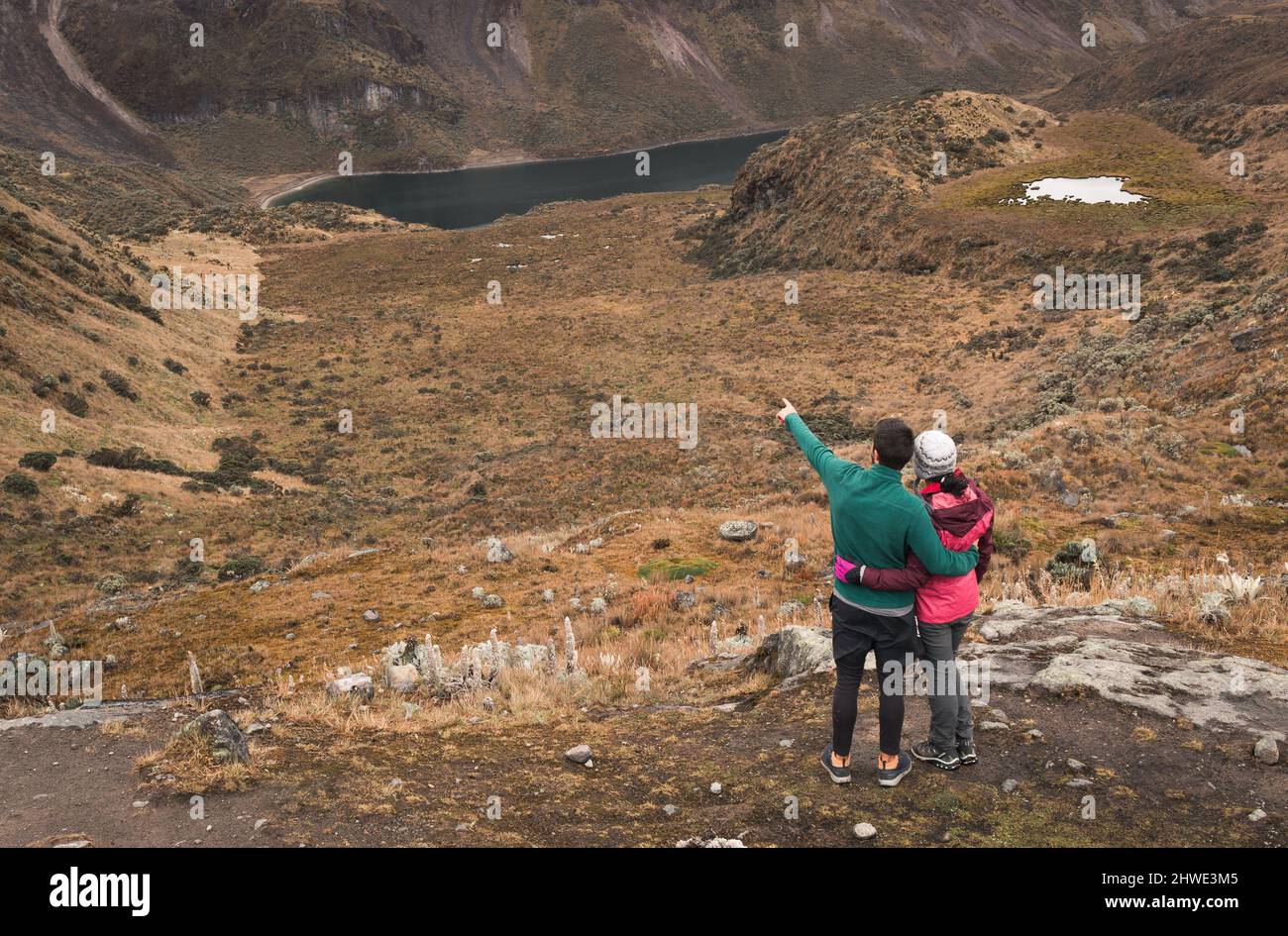 Coppia avventurosa abbraccia e guarda un paesaggio mozzafiato della valle del ghiacciaio con un lago Foto Stock