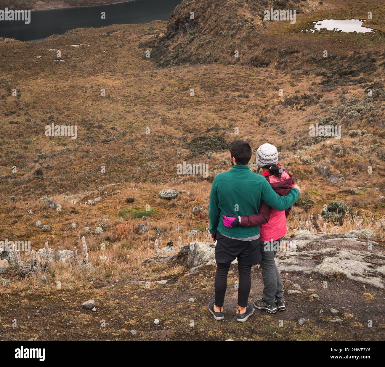 Coppia avventurosa abbraccia e guarda un paesaggio mozzafiato della valle del ghiacciaio con un lago Foto Stock