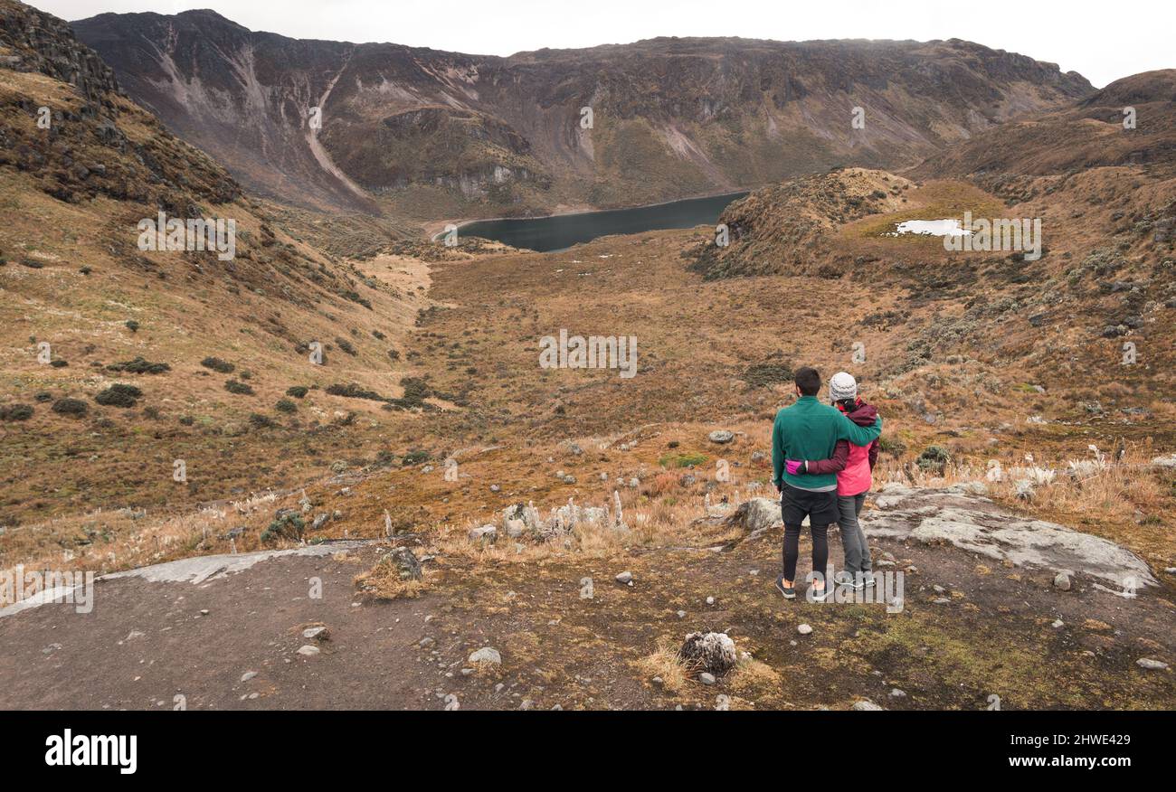 Coppia avventurosa abbraccia e guarda un paesaggio mozzafiato della valle del ghiacciaio con un lago Foto Stock