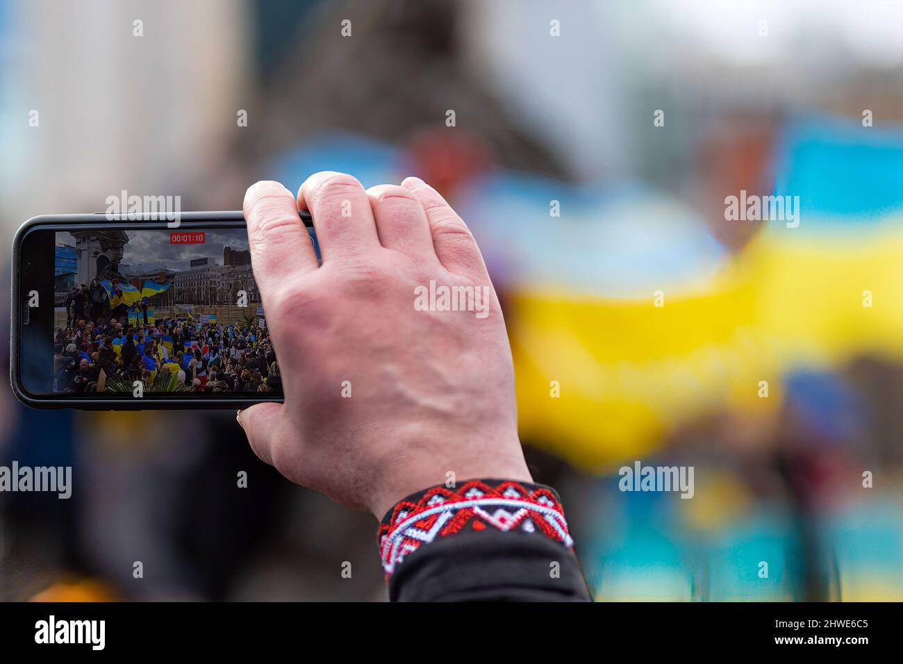 Manchester, Regno Unito. 05th Mar 2022. Un uomo registra altri manifestanti sul suo smartphone, durante la dimostrazione. Migliaia di persone si esibiscono nei giardini di Manchester Piccadilly per dimostrare sostegno e solidarietà a coloro che soffrono in Ucraina. Gli allievi hanno tenuto le bandiere ed hanno fatto i loro volti dipinti mentre altri hanno parlato sui gradini della statua della regina Vittoria. Credit: SOPA Images Limited/Alamy Live News Foto Stock