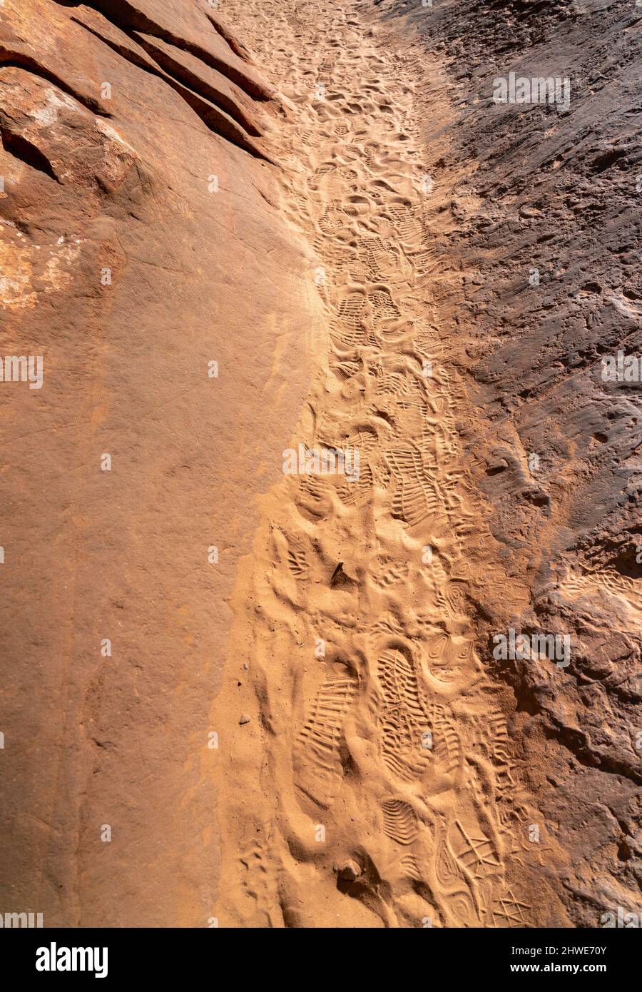 Vista del percorso stretto tra rocce grandi con stampe di scarpe sulla sabbia Foto Stock