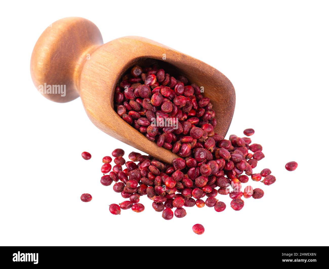 Semi di Sumac in paletta di legno, isolati su sfondo bianco. Bacche di Rhus secche intere Foto Stock