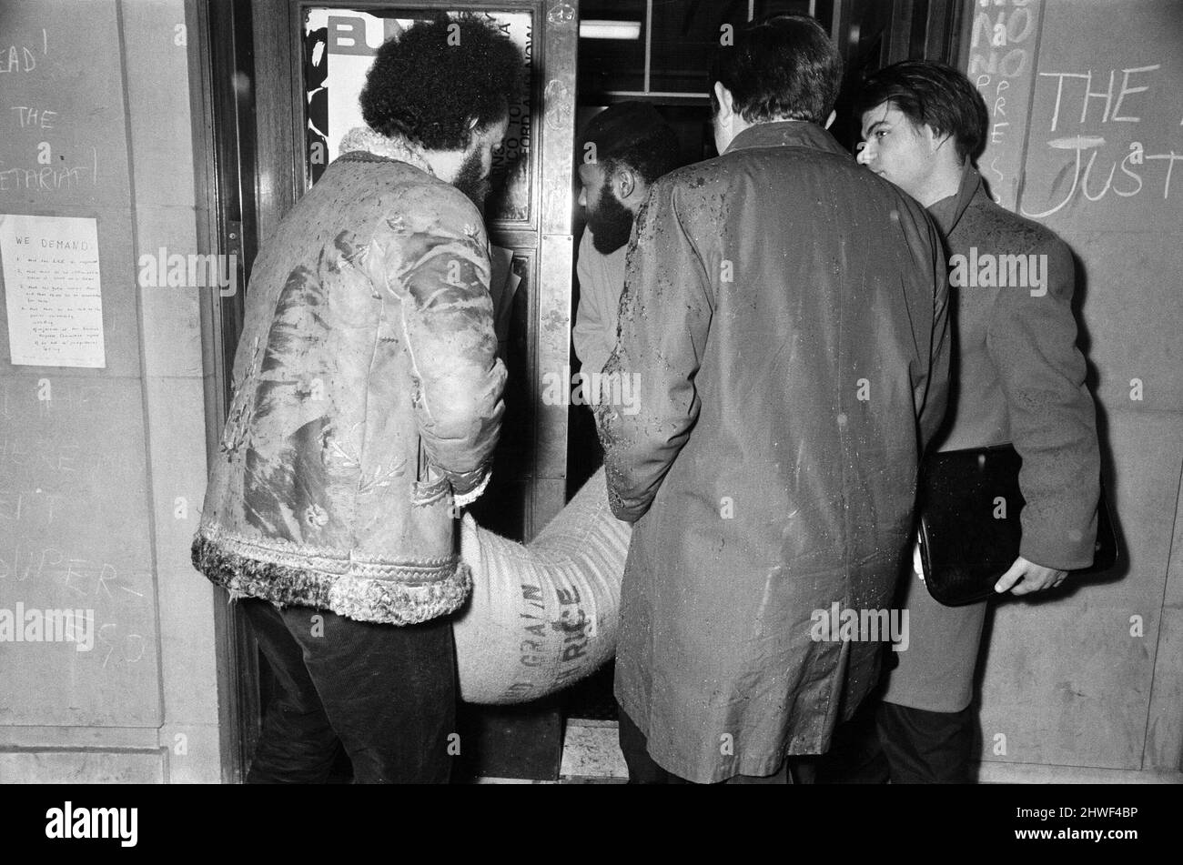 Gli studenti che occupano la sede centrale dell'Unione della London University a Malet Street, tengono un incontro per formulare i futuri piani d'azione. I manifestanti hanno detto che volevano costituire una base rivoluzionaria e istituire una London School of Economics in esilio, la LSE è stata chiusa a seguito di proteste da parte di studenti arrabbiati per l'installazione di cancelli di sicurezza in acciaio. Nella foto, Michael De Freitas (Michael X) sulla sinistra, e collega che consegna un sacco di riso alla sede centrale dell'ULU. 28th gennaio 1969. Foto Stock