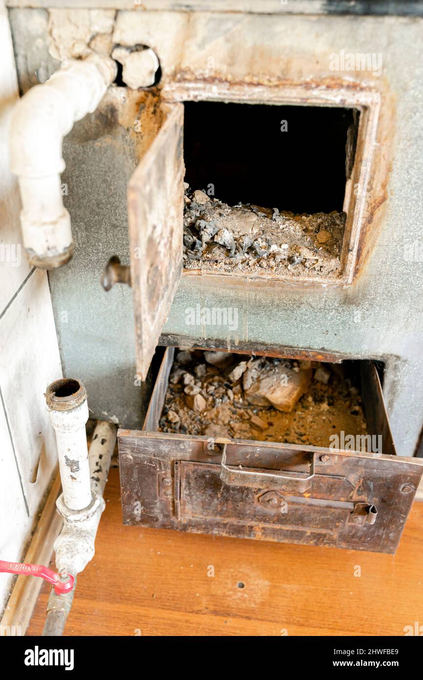 Vecchio forno arrugginito calore dal fuoco, con un cassetto a compartimento riempito di cenere Foto Stock