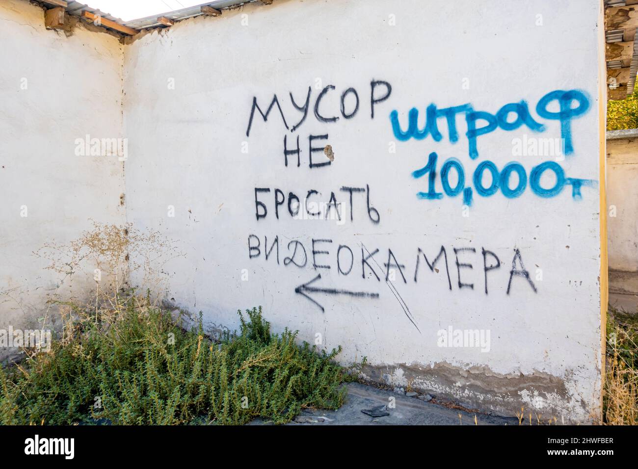 Avvertimento scritto sul muro di cemento 'non gettare spazzatura. Videosorveglianza. Tassa 10000 tenge' in lingua russa in Turkistan, Kazakistan Foto Stock