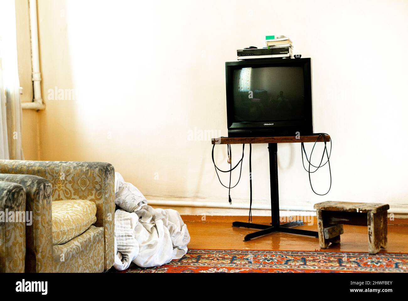 Soggiorno o camera da letto logoro con tv. Vecchio arredamento sovietico-uzbeco. Concetto - vivere ogni giorno in URSS sovietico interni Foto Stock