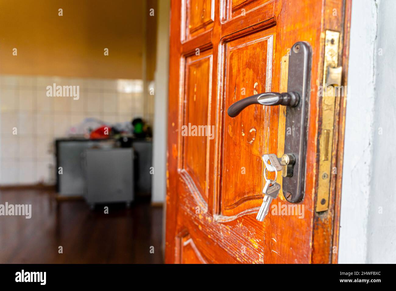 Le chiavi nella serratura e la maniglia della porta sulla vecchia porta di legno aperta Foto Stock