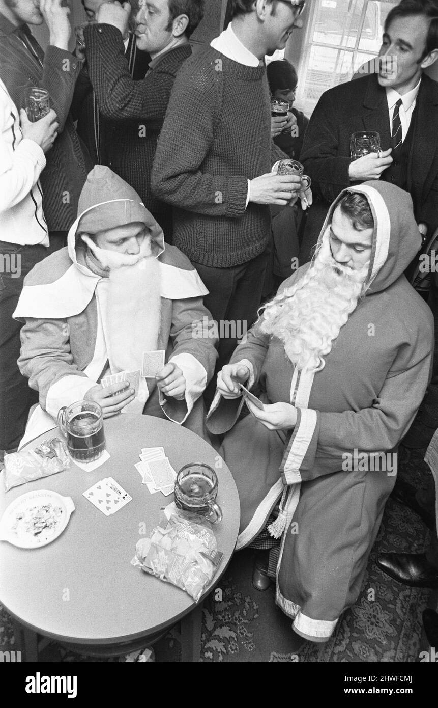 Dopo una dura giornata nella Grotta, con i bambini che tirano la barba e urlano e piangono perché temono l'uomo nella grande tuta rossa. Il nostro Babbo Natale si rilassa con una pinta e una partita di carte in The Bell, Reading. 7th dicembre 1970 Foto Stock