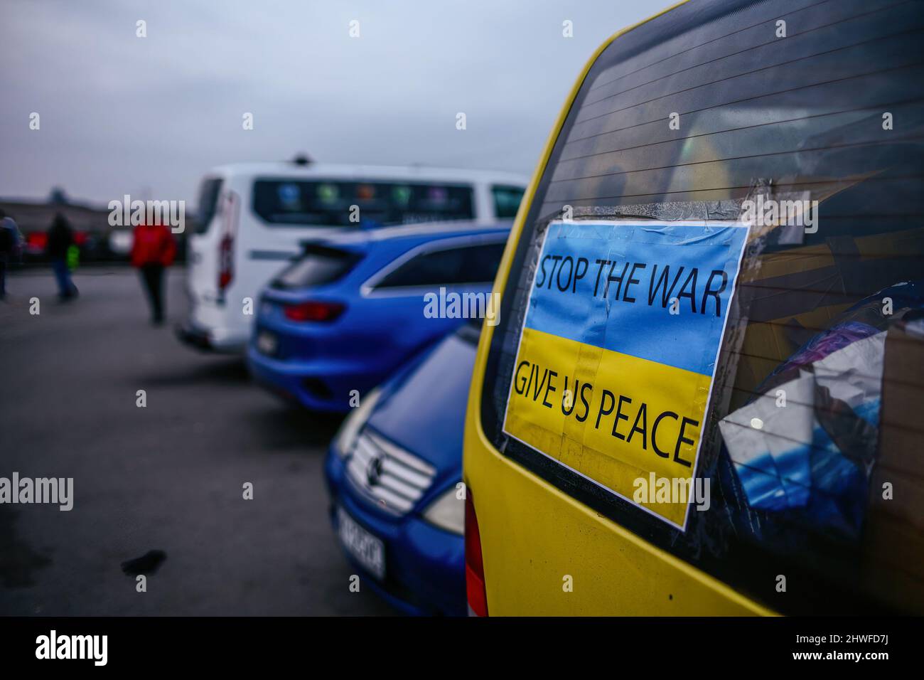 Una bandiera Ucraina con le parole "Stop the war, give us peace” è vista sulla finestra di un'automobile usata per trasportare i rifugiati dalle zone colpite dalla guerra. Attraversamento di frontiera polacco-ucraino a Medyka. Dall'inizio dell'invasione russa dell'Ucraina, circa 700.000 persone sono fuggite in Polonia per sfuggire alla guerra. Nonostante la disinformazione considerevole e gli incidenti isolati, i rifugiati ucraini sono accolti con empatia, aiuto e comprensione, ma molti esperti umanitari indicano che, con un afflusso così enorme di persone, una crisi potrebbe verificarsi in poche settimane. Foto Stock