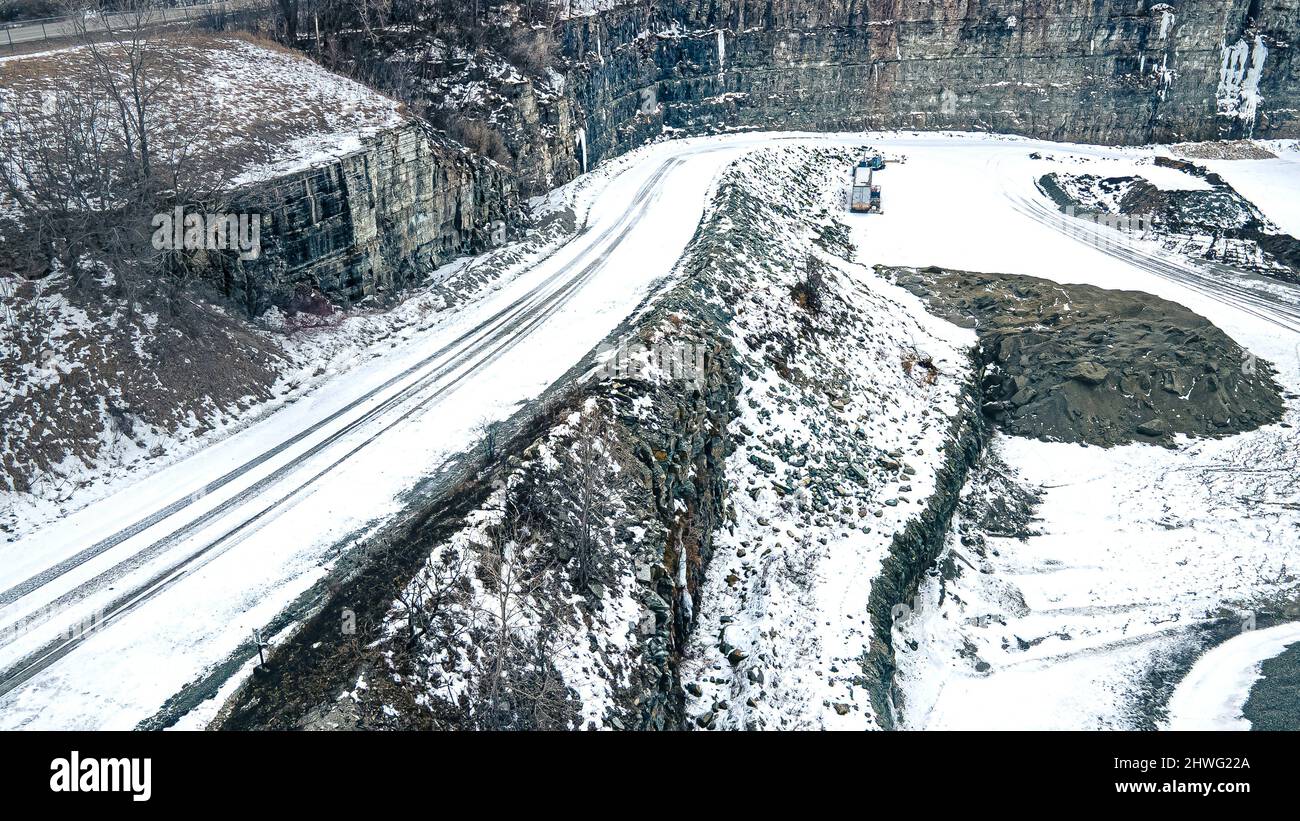 Durante l'inverno, una strada di ghiaia coperta di neve si addentra più a fondo nella cava ghiacciata. Foto Stock