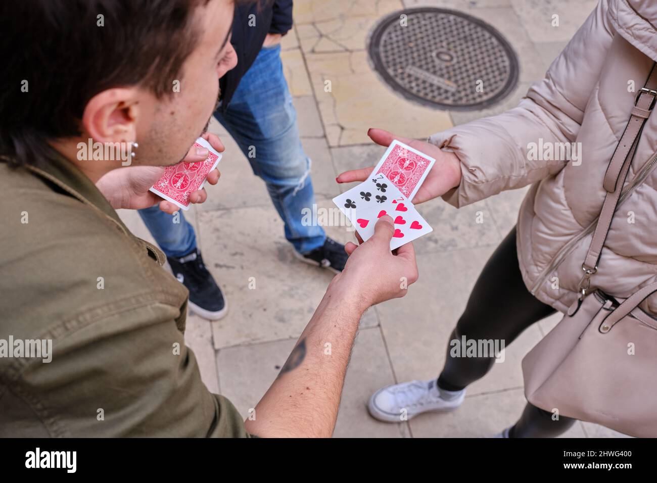 Mago di strada che esegue trucchi con carte utilizzando il pubblico Foto Stock