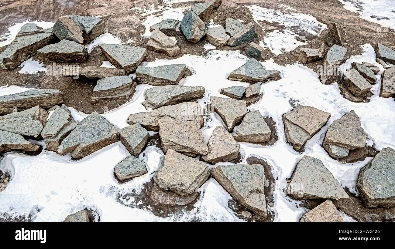 Grandi rocce e pietre raccolte in una cava di roccia con neve che si scioglie sui lati che saranno utilizzati per paesaggio paesaggistico. Foto Stock