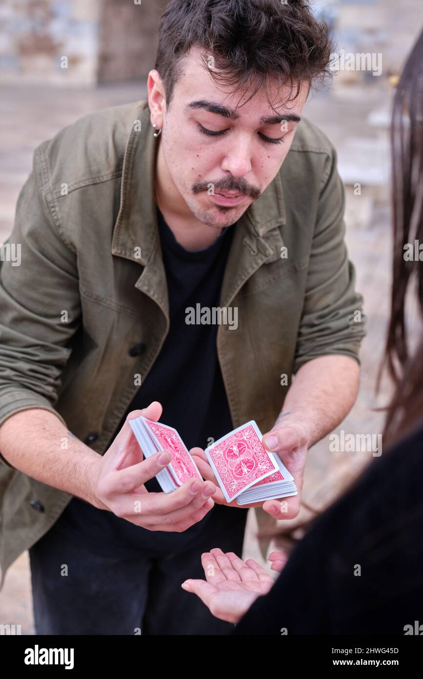 Artista di strada che divide una pila di carte in due per eseguire un trucco magico. Foto Stock