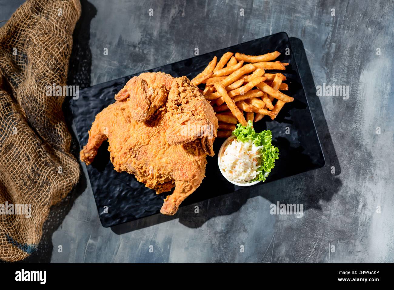 Pollo fritto croccante alla primavera (pieno) con patatine fritte e bagno mayo in un piatto nero vista dall'alto su sfondo scuro fast food Foto Stock