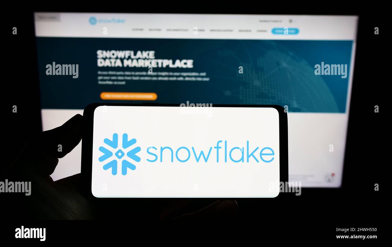 Persona che tiene lo smartphone con il logo della società di software statunitense Snowflake Inc. Sullo schermo di fronte al sito Web. Mettere a fuoco sul display del telefono. Foto Stock