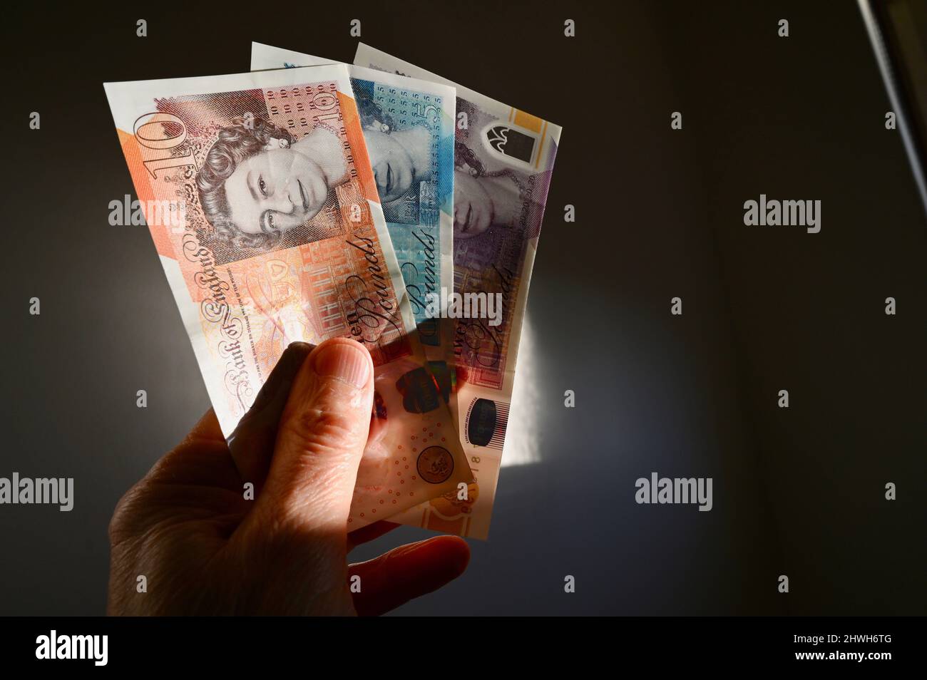 Primo piano di un uomo anziano che detiene varie note sterlina Foto Stock