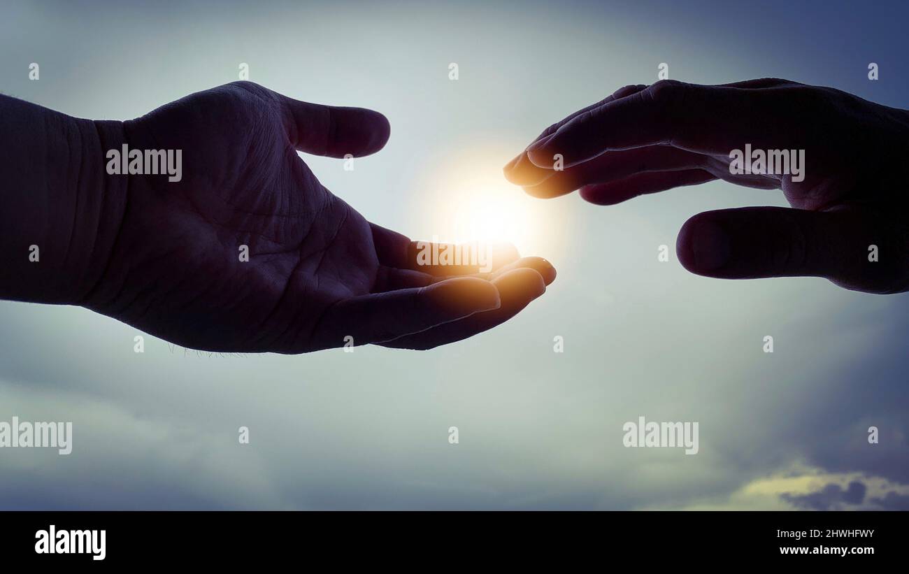 Due mani cercano di raggiungere la luce brillante. Foto Stock