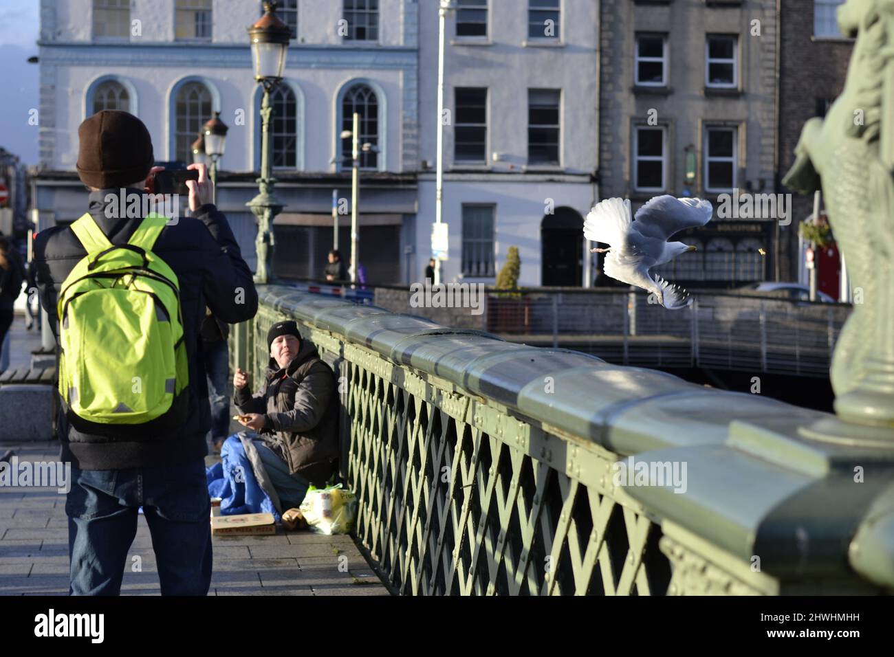 Un uomo che scatta una foto di un senzatetto su un ponte a Dublino, in Irlanda. Foto Stock