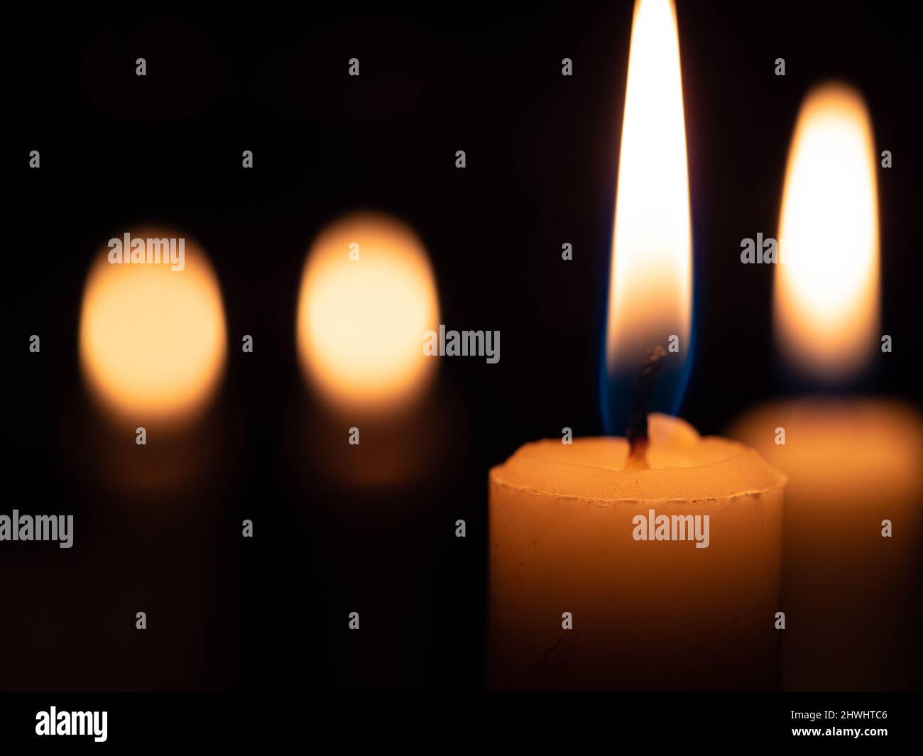 Immagine con sfondo nero due candele accese a destra con due luci fuori fuoco a sinistra Foto Stock