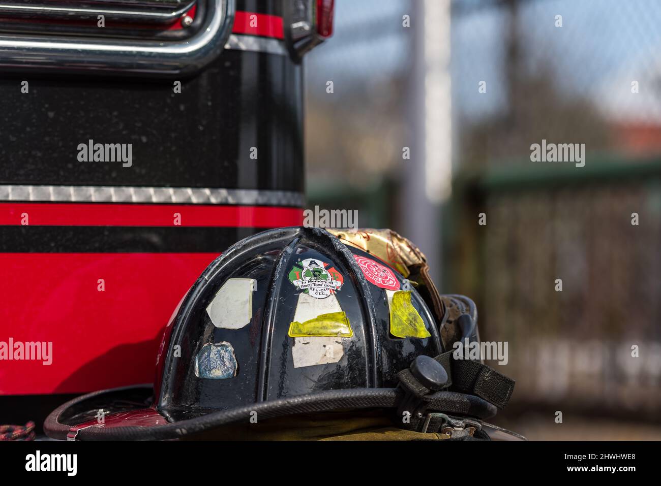 Primo piano del casco dei pompieri appoggiato sul paraurti del camion dei pompieri. Foto Stock