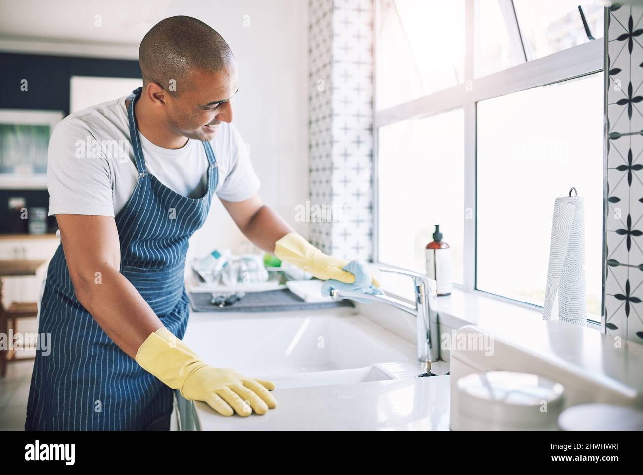 Mi piace vedere la mia riflessione attraverso le mie superfici. Scatto di un giovane uomo che pulisce una cucina a casa. Foto Stock
