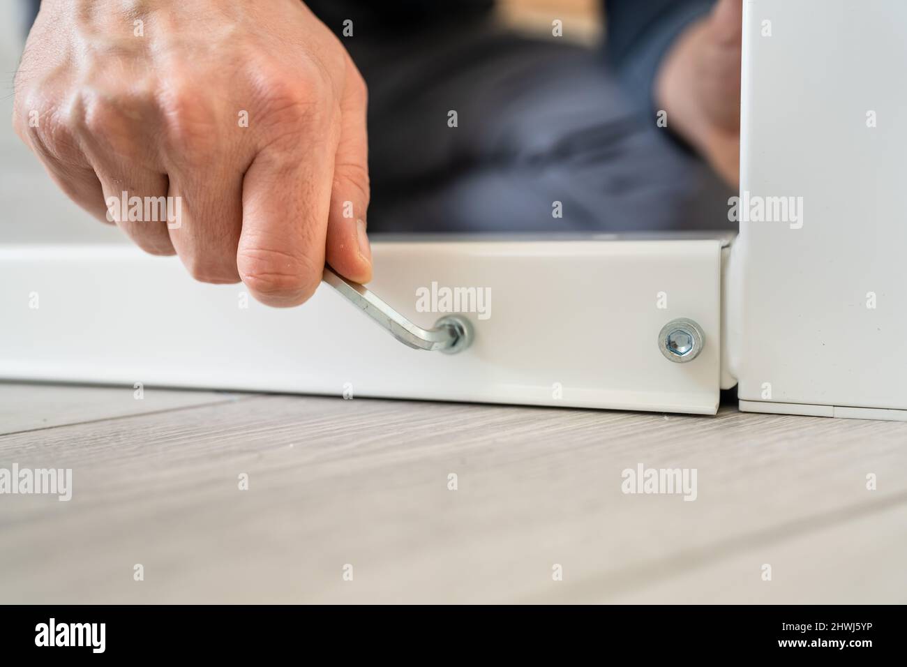 Un uomo sconosciuto maschio caucasico seduto sul pavimento a casa mettendo insieme Self Assembly Mobili diy assemblaggio tenendo parti e istruzioni reali Foto Stock