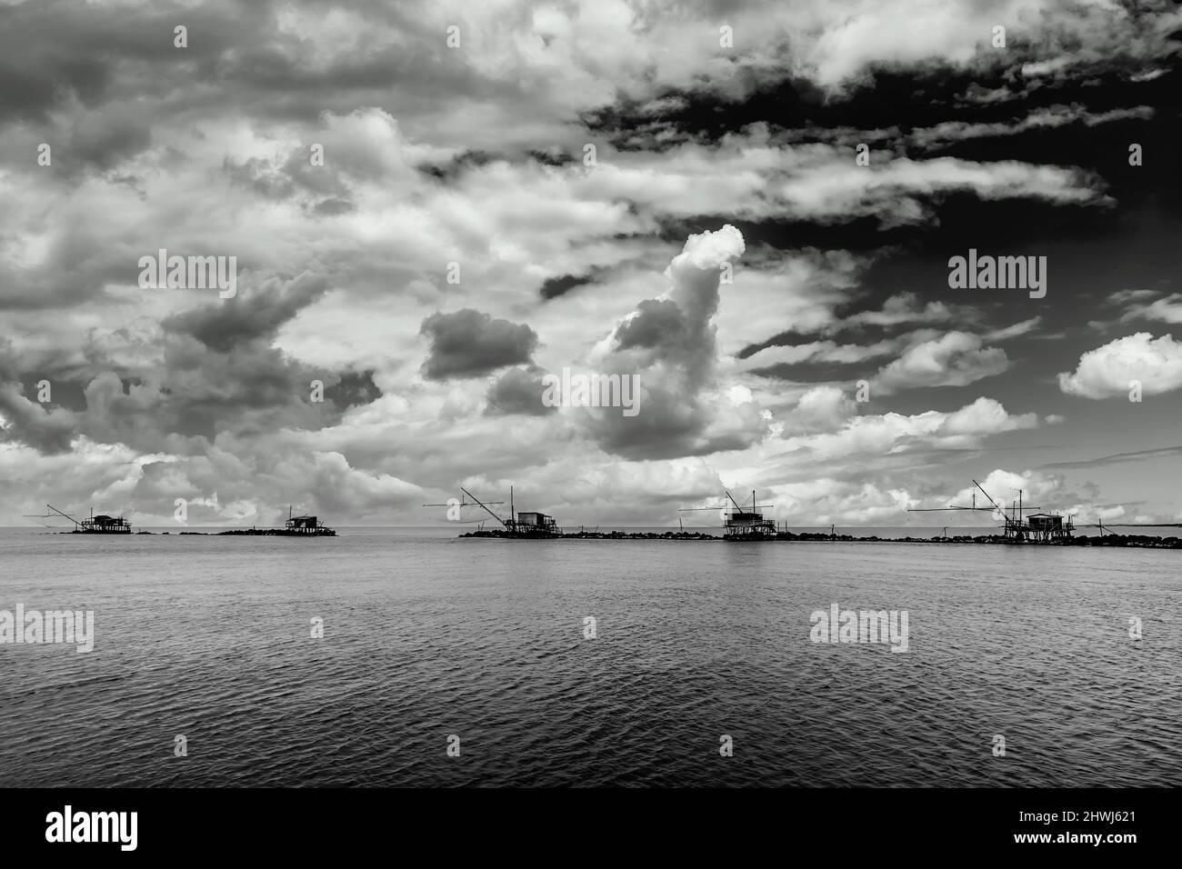 Cinque capanne di pesca a rete a Marina di Pisa, Toscana, Italia, sotto un cielo drammatico, in bianco e nero Foto Stock