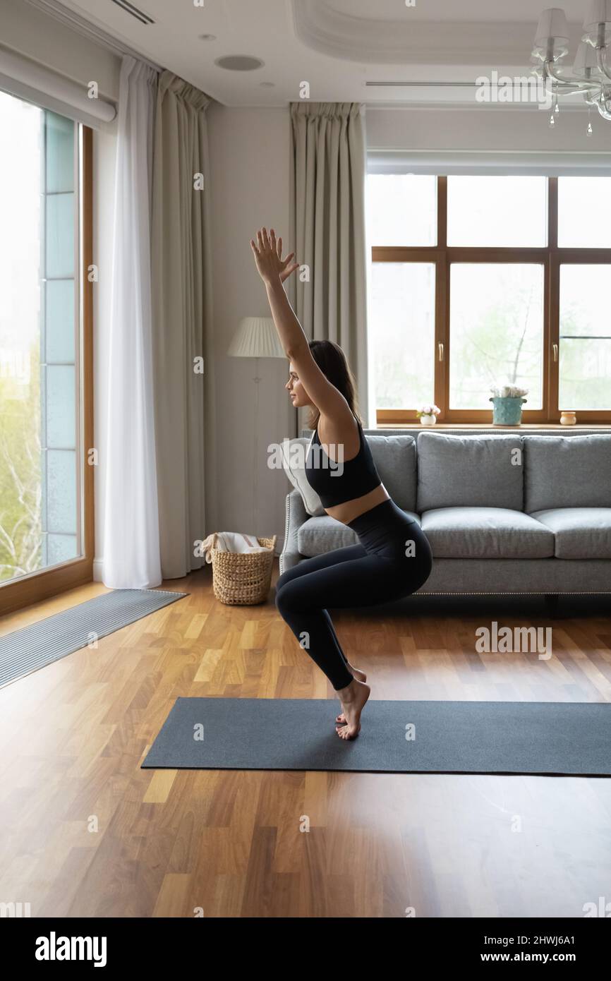 Bella donna sottile che pratica yoga a casa Foto Stock