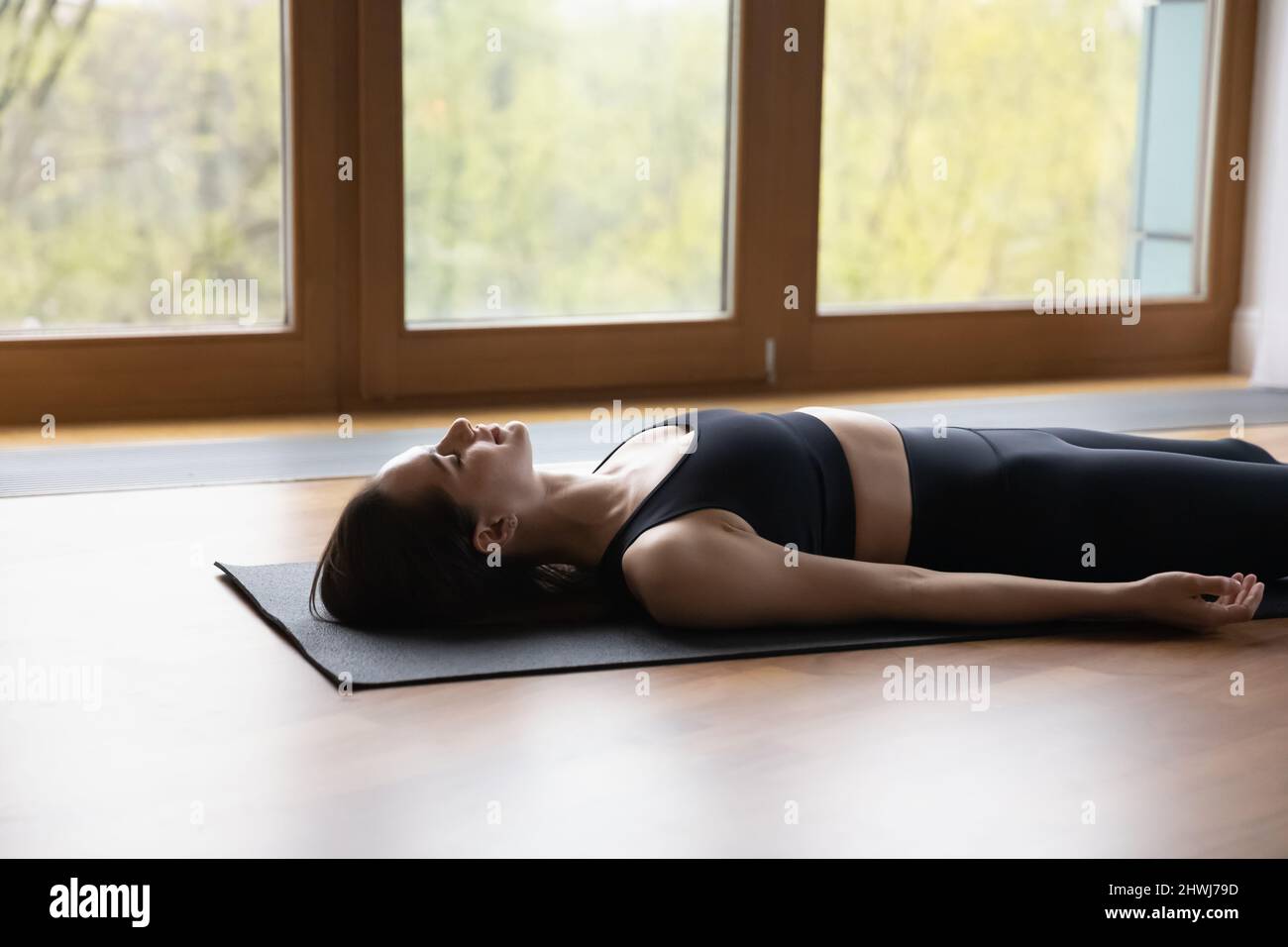 Donna sdraiata sul tappeto facendo il cadavere o il corpo morto asana Foto Stock