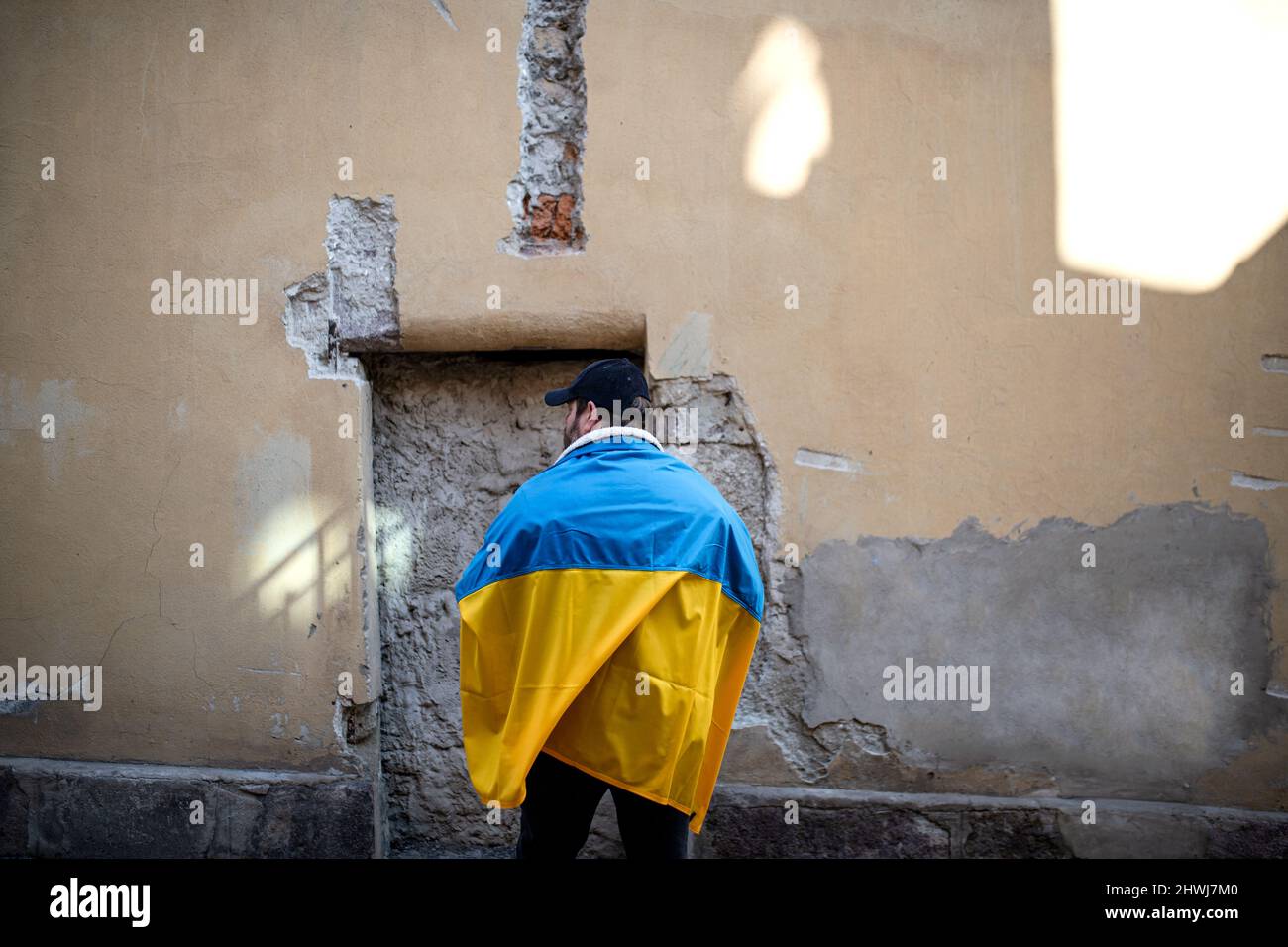 Protestante coperto di bandiera Ucraina blu e gialla che protestano contro la guerra in Ucraina per strada Foto Stock