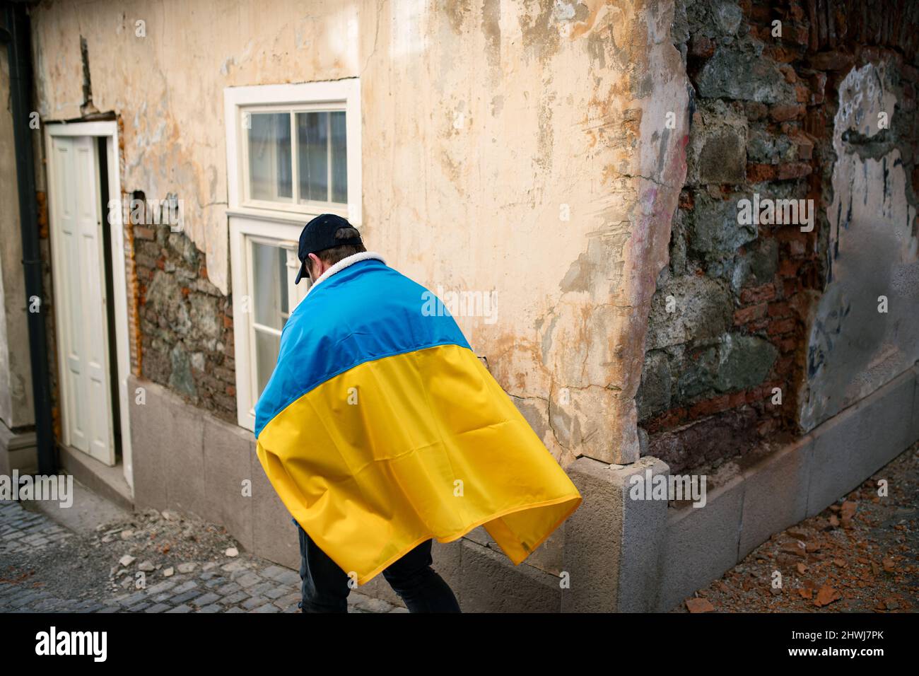 Protestante coperto di bandiera Ucraina blu e gialla che protestano contro la guerra in Ucraina per strada Foto Stock