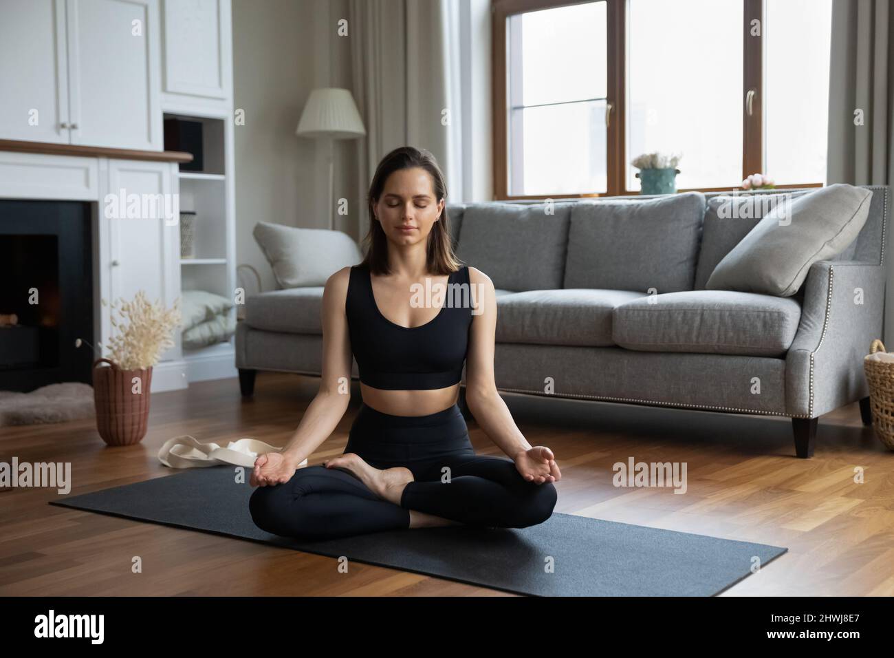 Bella donna meditating seduta sul tappeto in soggiorno Foto Stock