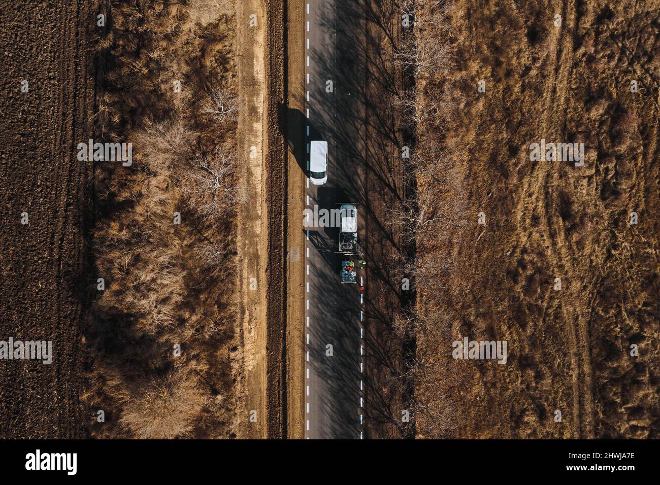 I lavoratori della strada utilizzano le macchine per dipingere i cartelli trafic su una superficie asfaltata fuori dalla città. Segnaletica stradale. Lavoratori e spruzzatori di vernice per strade. Foto Stock