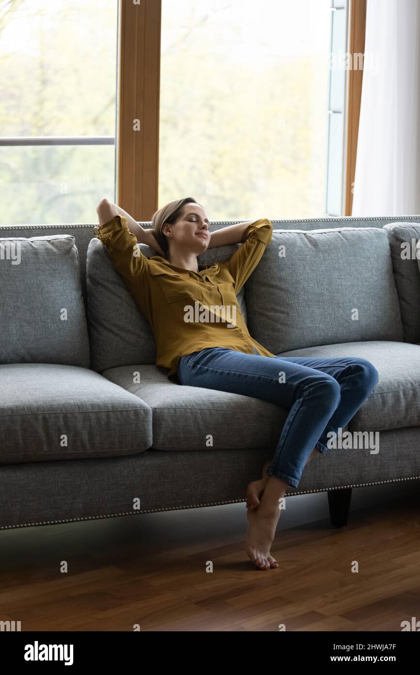Vista verticale donna serena relax sul divano con gli occhi chiusi Foto Stock