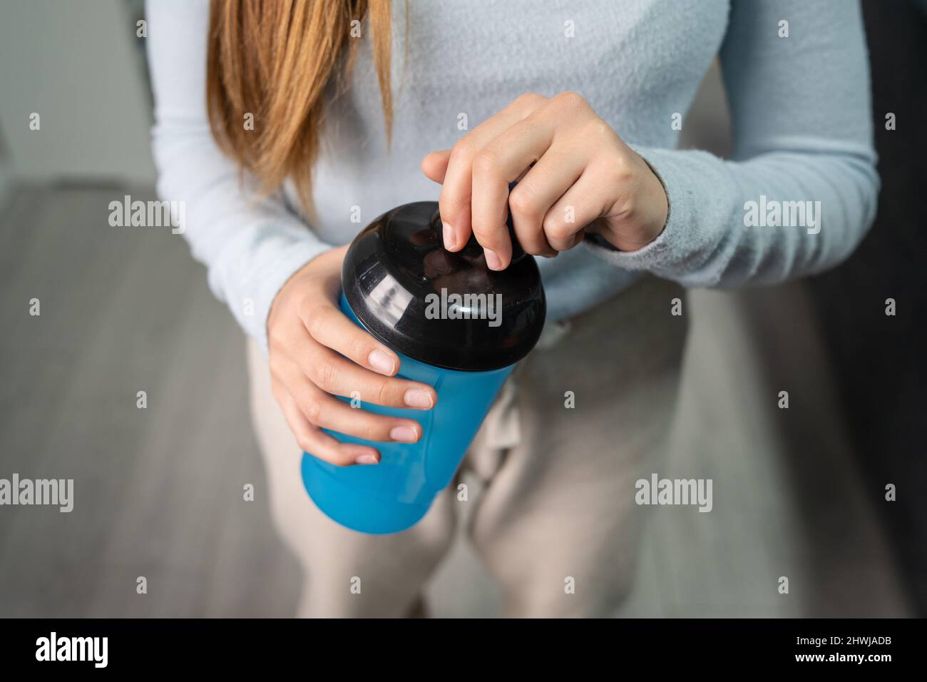 Primo piano sulle mani di donna caucasica sconosciuta che tiene il supplemento scuotere mentre ci si trova in camera all'apertura o alla chiusura di casa vista frontale Foto Stock