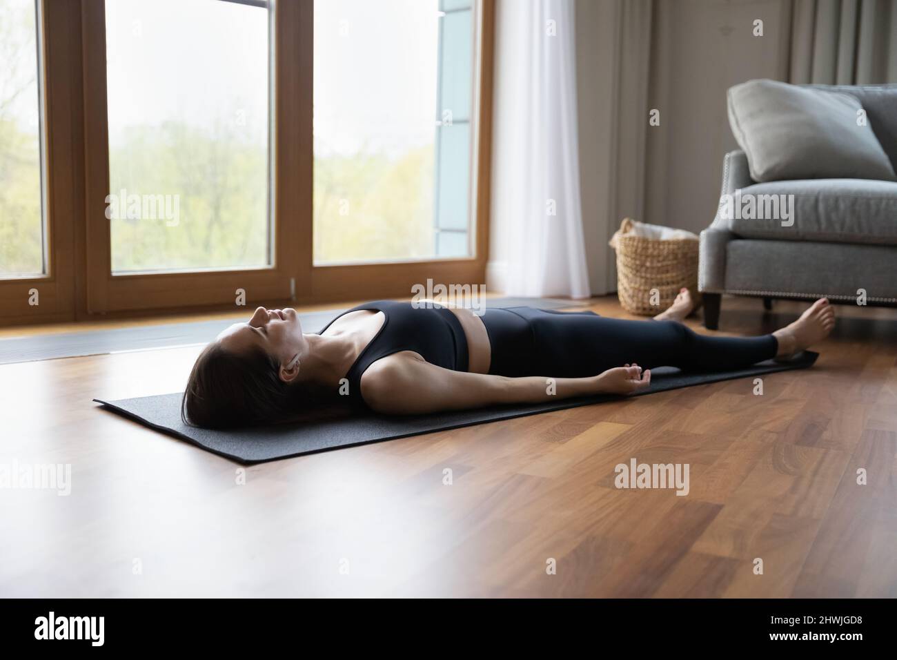 La giovane donna ascolta la musica meditativa attraverso gli auricolari che si rilassano dopo lo yoga Foto Stock